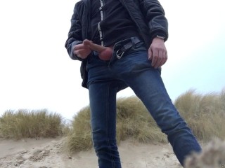 young man urinates in the dunes