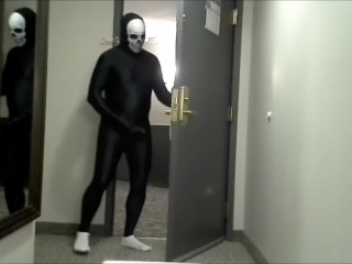 skeleton faced white socked black morphman in front of hotel room