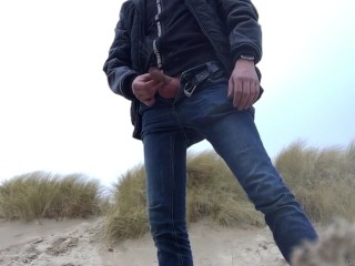 young man urinates in the dunes