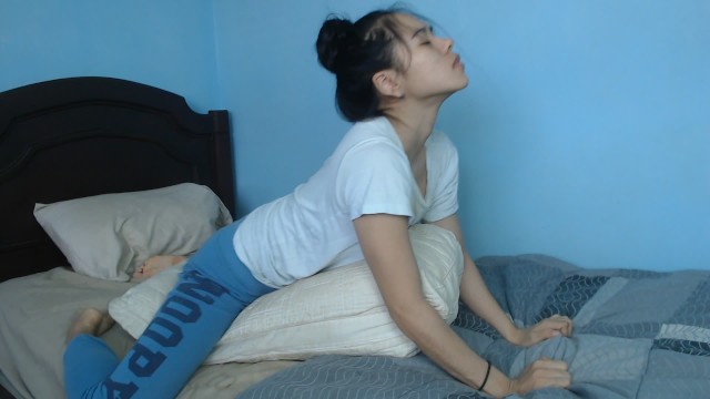 A passionate Asian girl makes herself by rubbing against a pillow